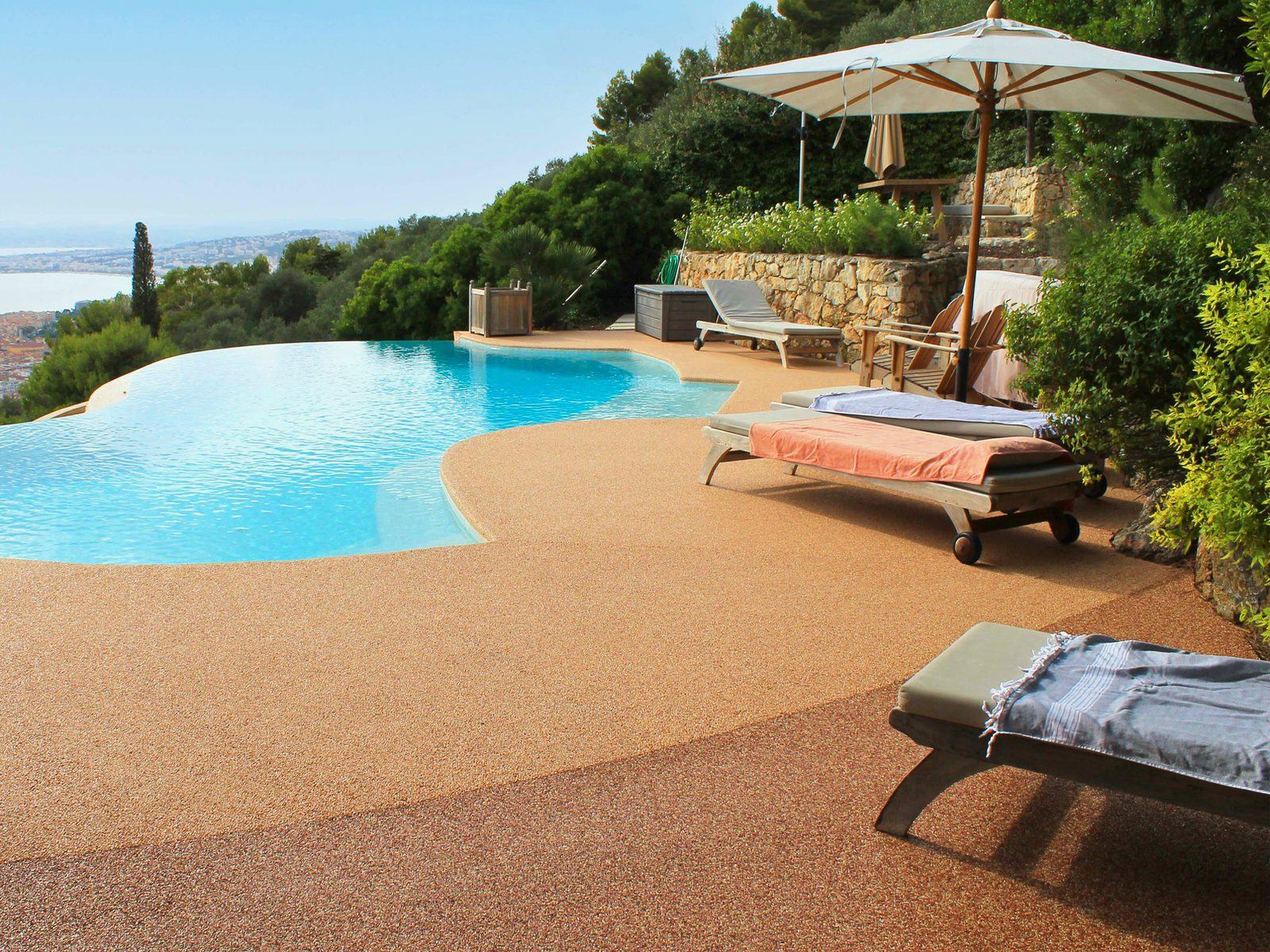 Playa de piscina infinita con pavimento Resineo en tono terracota y vistas al mar