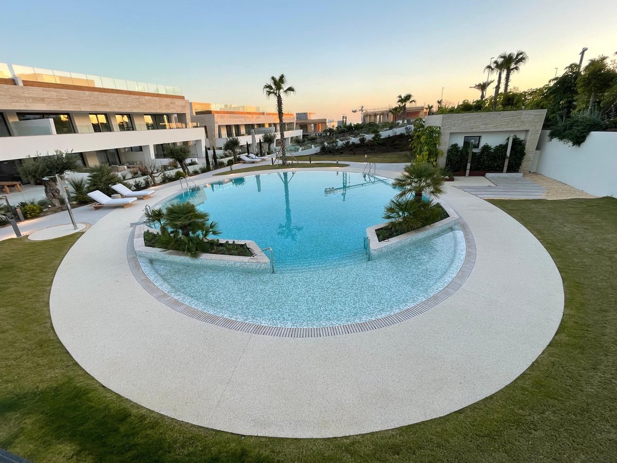 Piscina circular de comunidad residencial con pavimento Resineo al atardecer